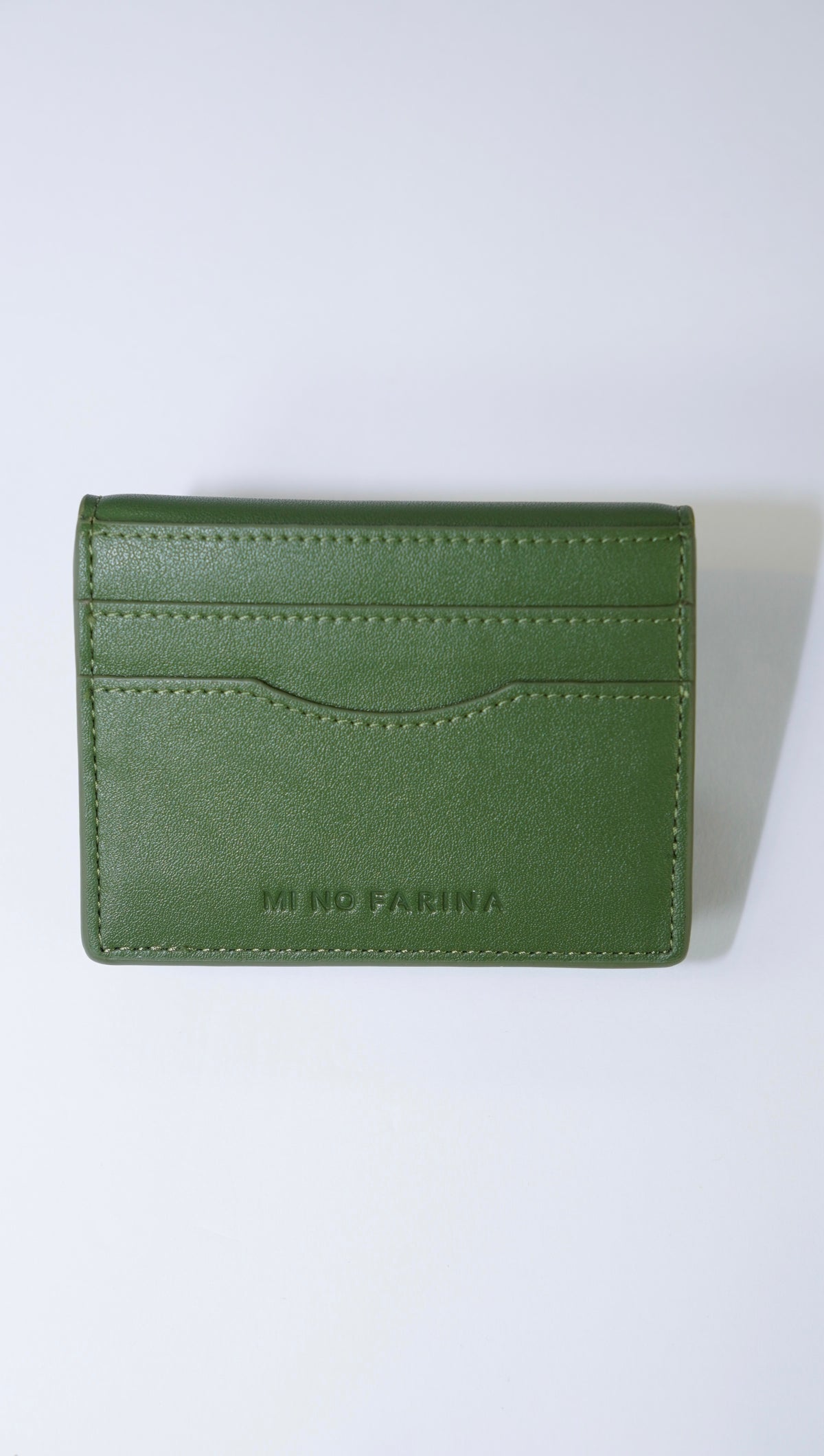 An olive green leather card holder wallet with 'MI NO FARINA' debossed on the front, displayed on a clean white background.