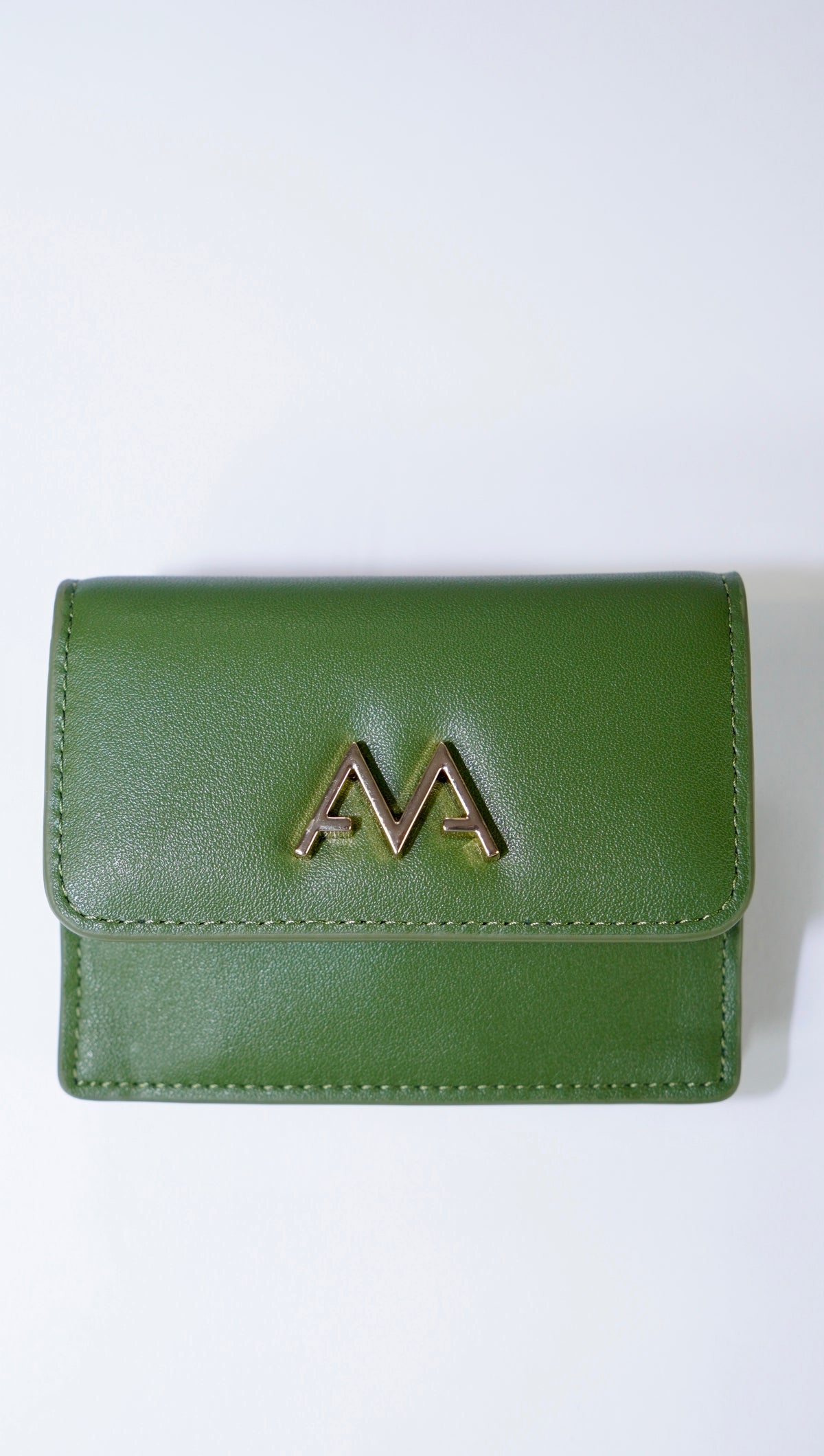 A green leather wallet with a prominent gold 'M' logo on the front flap, photographed against a plain white background.